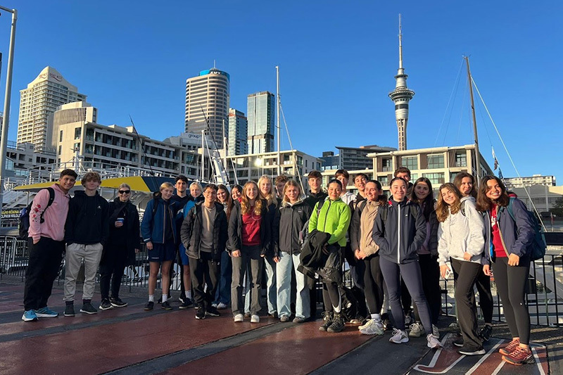 Macleans College international students exploring Auckland's Viaduct Harbour, with the Sky Tower pictured in the background